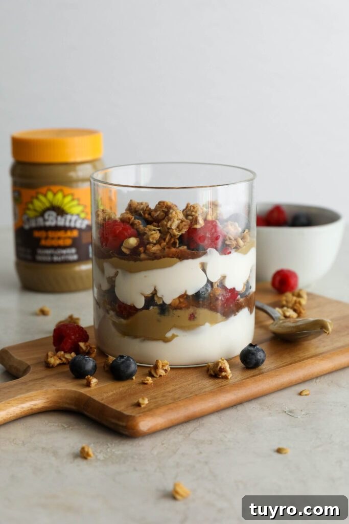 SunButter Berry Spring Parfait in glass jar on wooden board with berries and granola sattered
