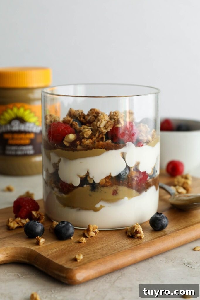SunButter Berry Spring Parfait in glass jar on wooden board with berries and granola sattered