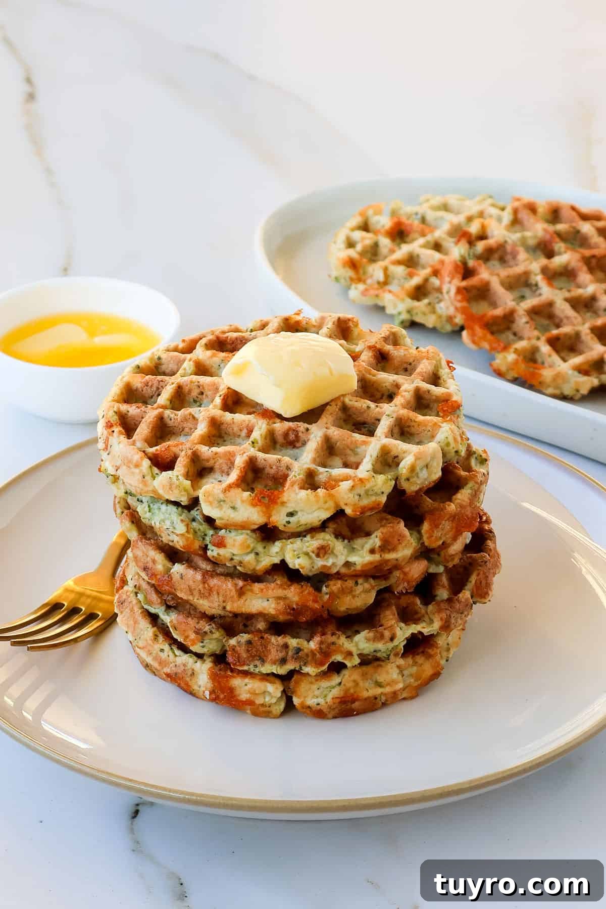 Broccoli Cheddar Waffles Recipe 9 Broccoli cheese waffles stacked on a plate topped with a knob of butter.