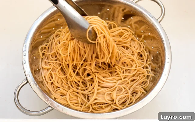 Creamy Walnut Pesto Pasta Recipe for Quick Weeknight Meals 5 Tongs holding pasta in a collander.