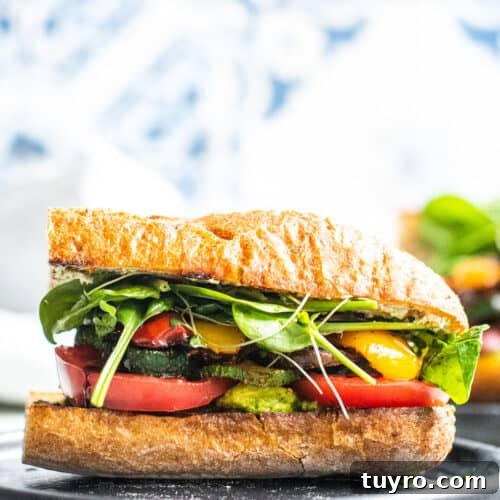 Strait on shot of vegetable sandwich on a dark gray plate with white and blue background.