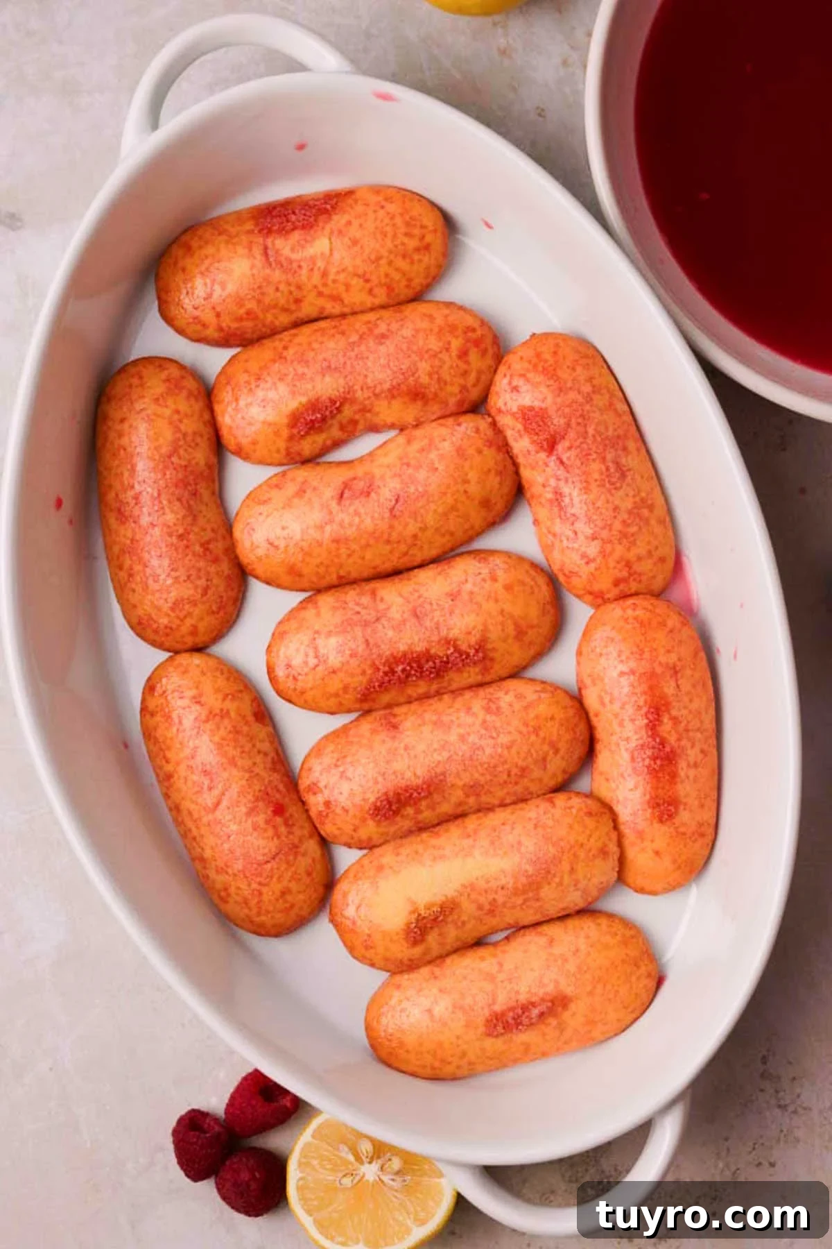 Raspberry Tiramisu Recipe: Light, Creamy Berry Dessert 12 layering syrup soaked ladyfingers in a ceramic casserole dish