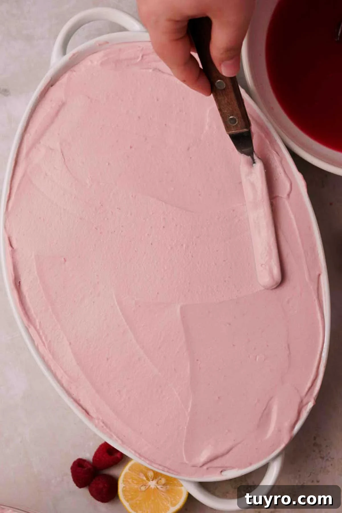 Raspberry Tiramisu Recipe: Light, Creamy Berry Dessert 13 smoothing the top of raspberry tiramisu with an offset spatula
