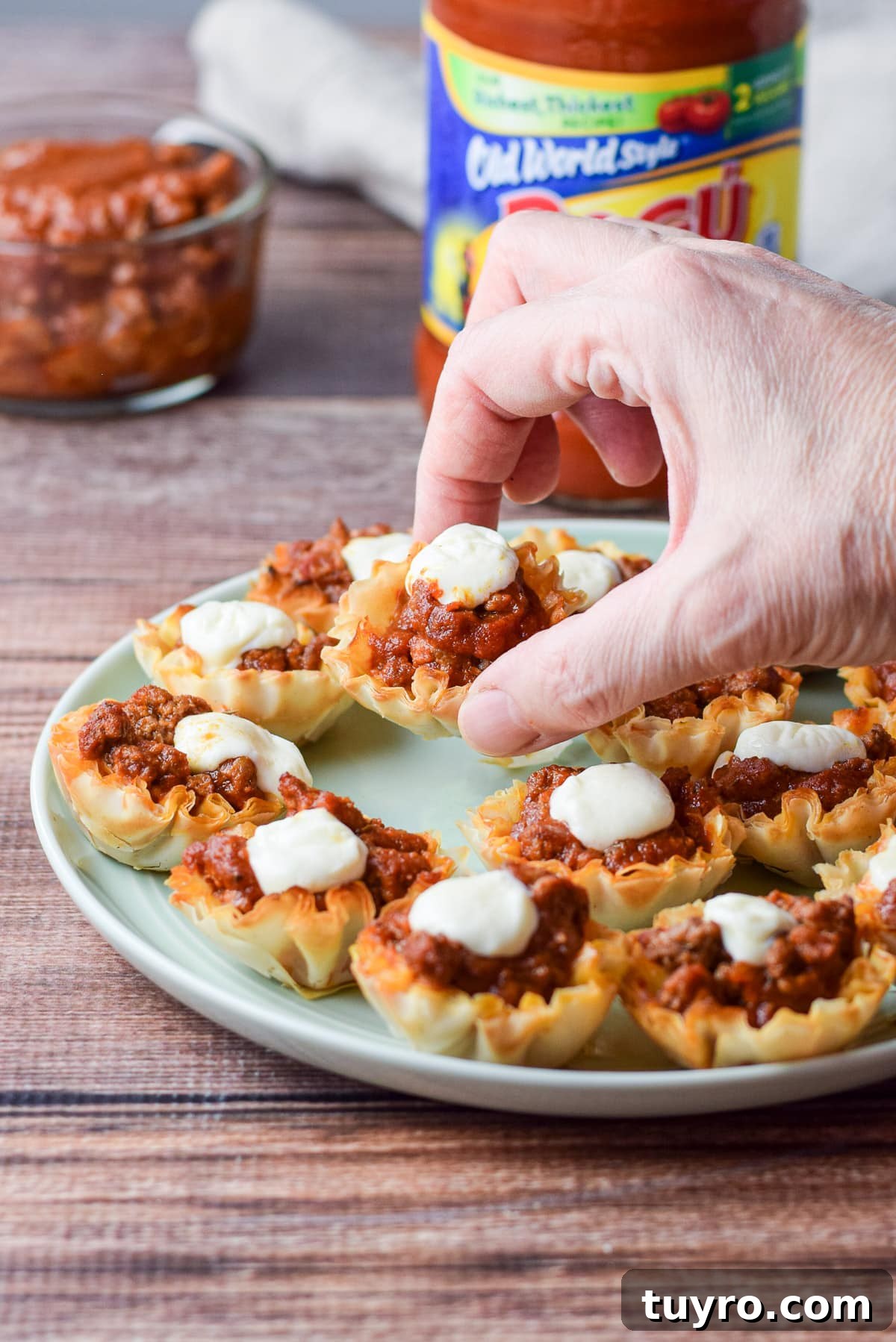 Savory Sauced Beef Bites: Perfect Party Appetizer Recipe 6 A woman's hand holding one of the beef appetizer's over the plate of the appetizer