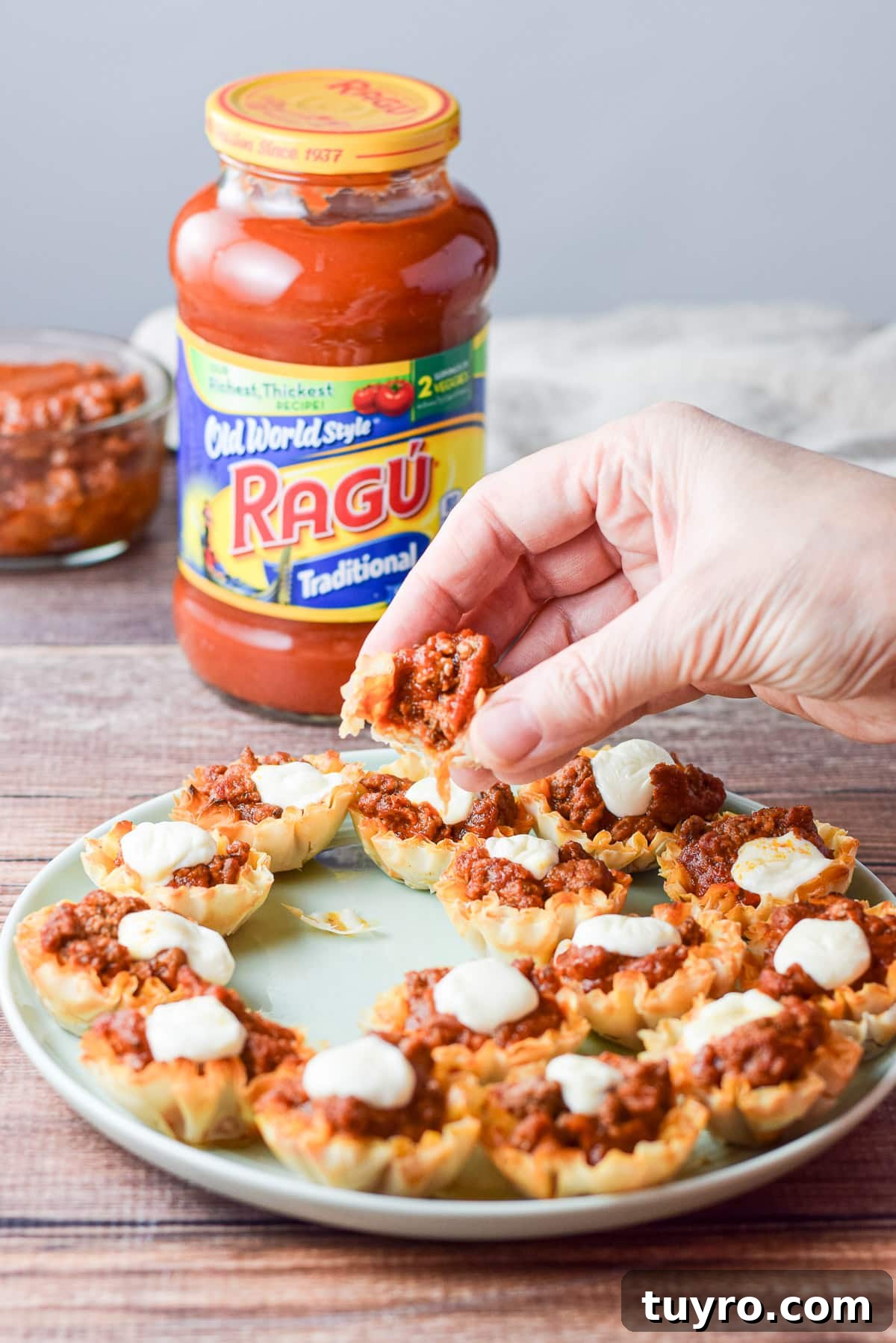 Savory Sauced Beef Bites: Perfect Party Appetizer Recipe 7 The woman's hand holding the appetizer with a bite out of it over the platter with the sauce in the back