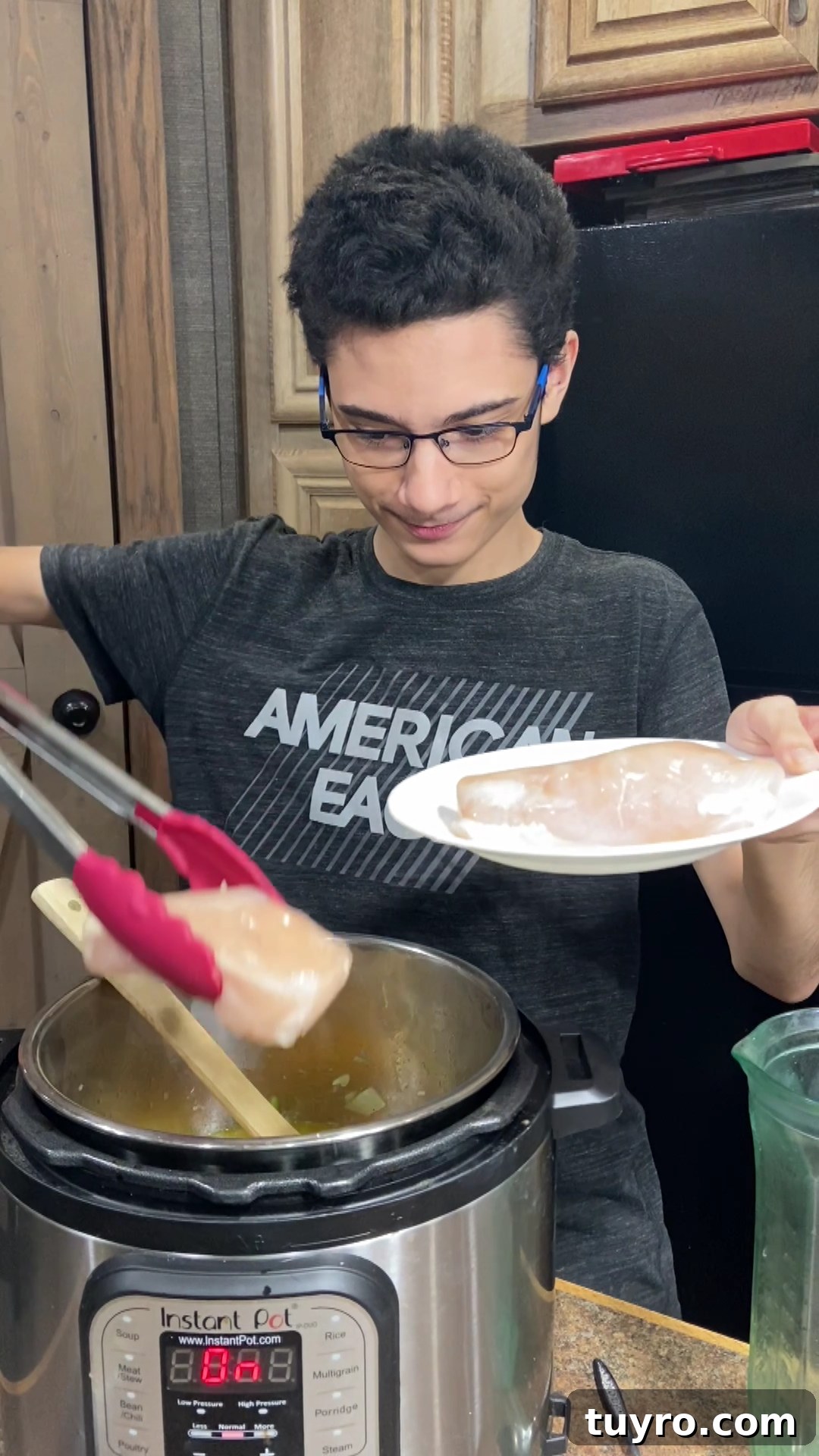 Chef Christian using silicone tongs to add chicken breasts to Instant Pot