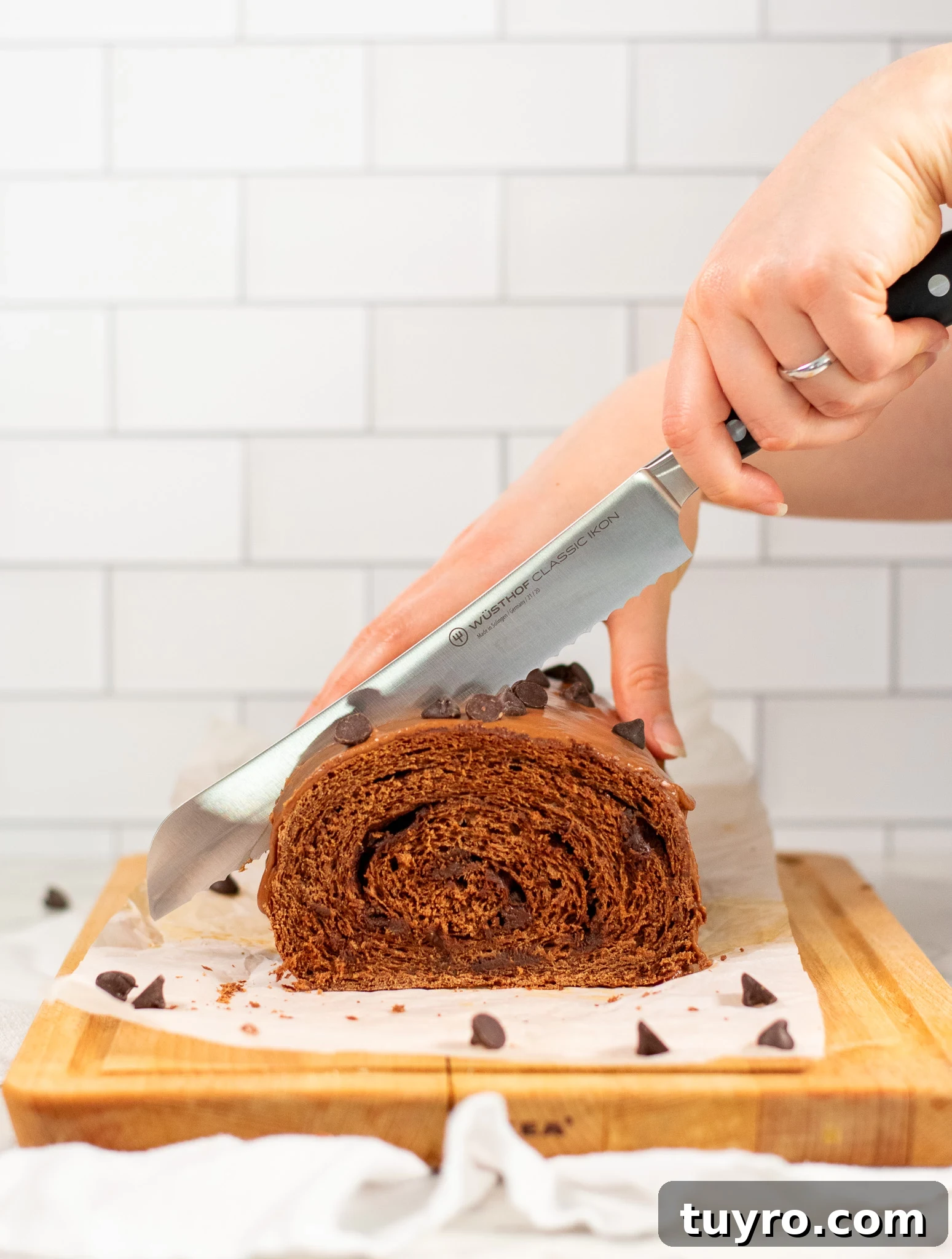 Chocolate Swirl Bread Recipe — Soft Homemade Choco Loaf 8 A person cutting a slice of chocolate swirl bread.