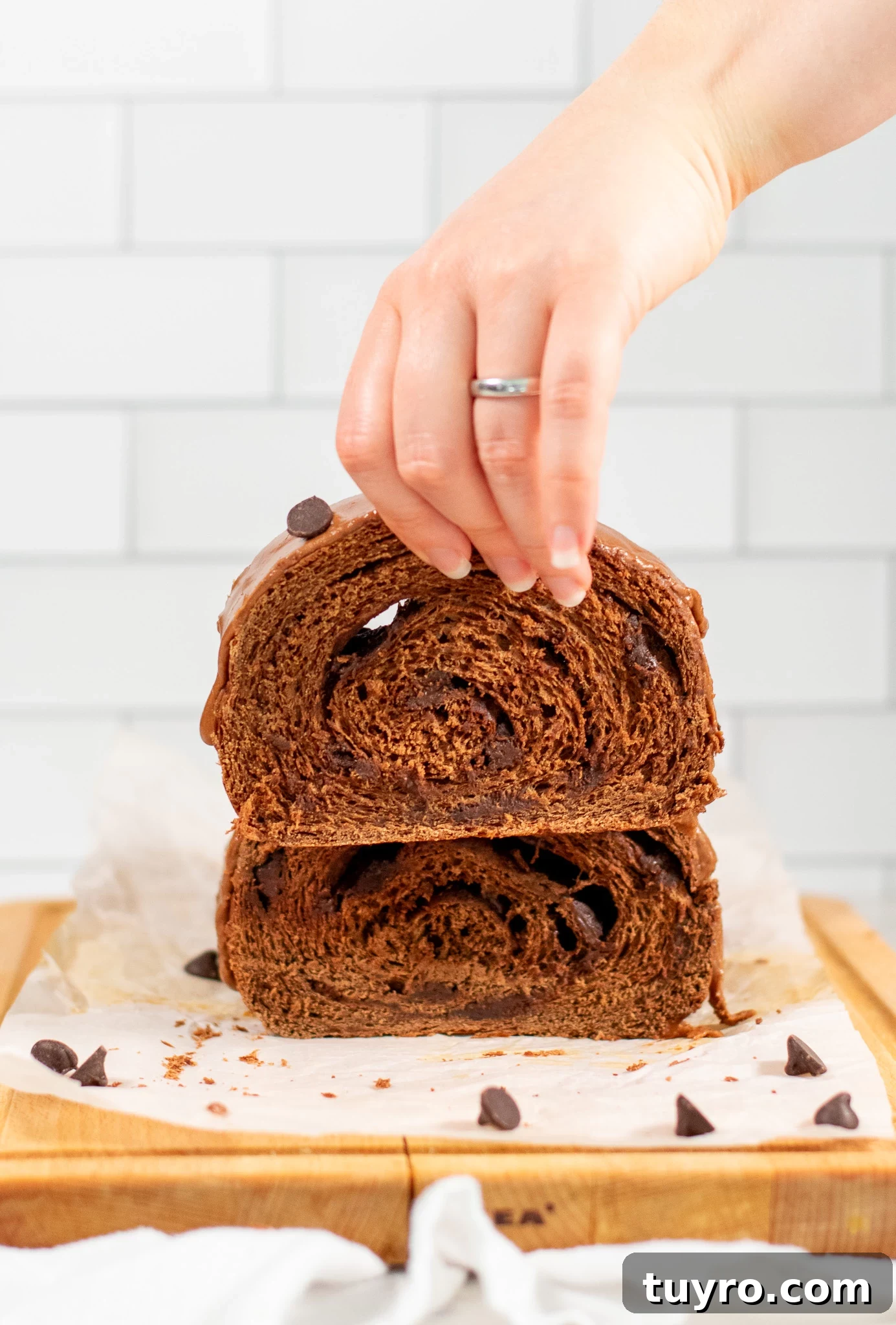 Chocolate Swirl Bread Recipe — Soft Homemade Choco Loaf 9 A person lifting a piece of chocolate swirl bread.