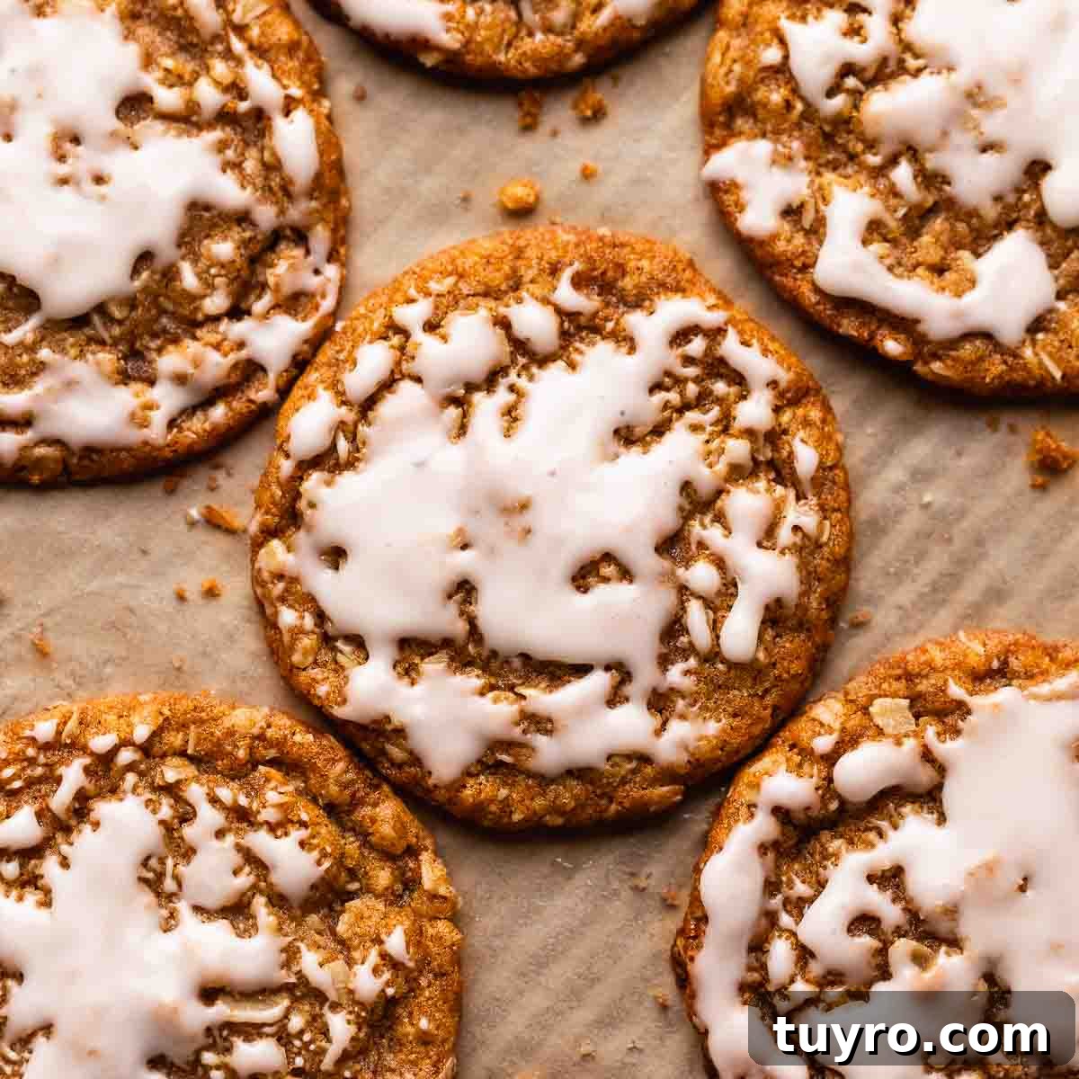 Soft Iced Oatmeal Cookies Recipe with Chewy Texture and Vanilla Glaze 7 Oatmeal cookies with icing on a parchment lined baking tray.