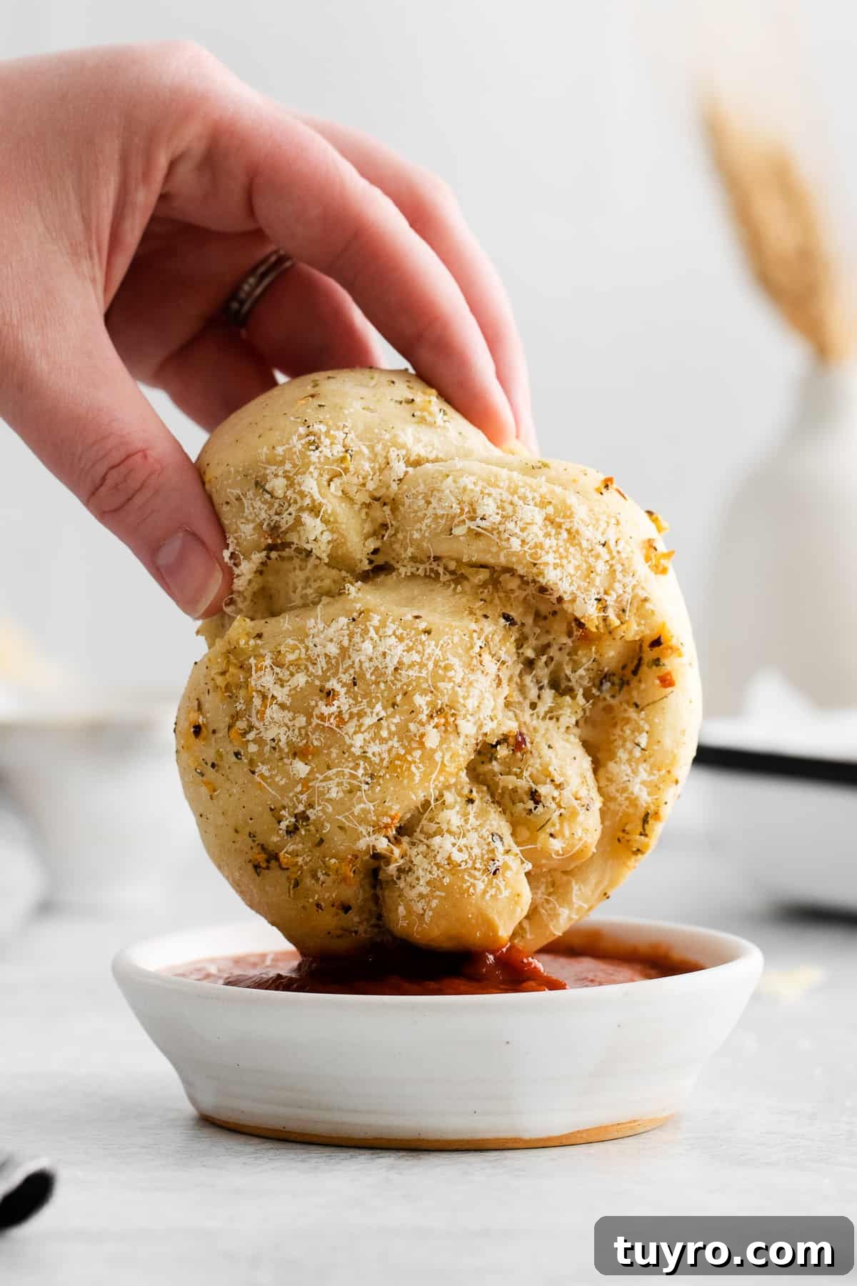 Homemade Parmesan Garlic Knots Recipe 2 Dipping a garlic knot into marinara sauce.
