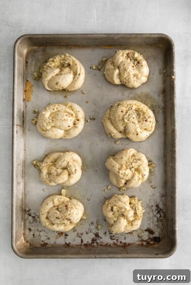Homemade Parmesan Garlic Knots Recipe 14 Garlic knots with oil and spices on a baking sheet.