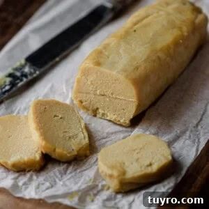 log of cashew cheese on parchment paper with knife.