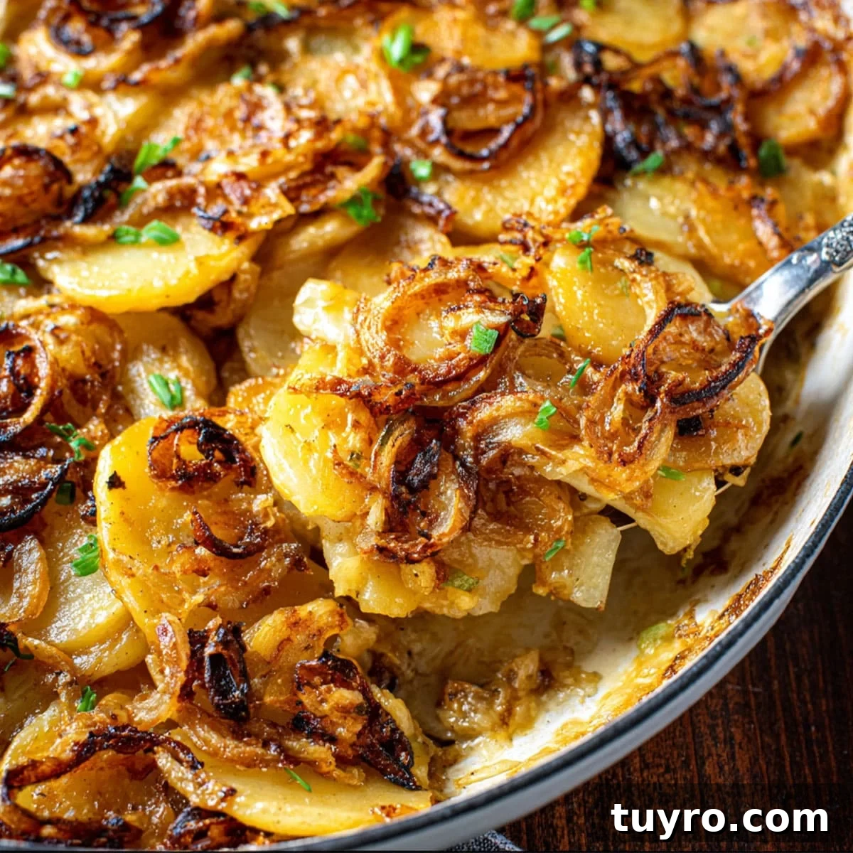 Close-up of crispy fried onion scalloped potatoes in a ceramic dish, featuring caramelized onions and melty cheese