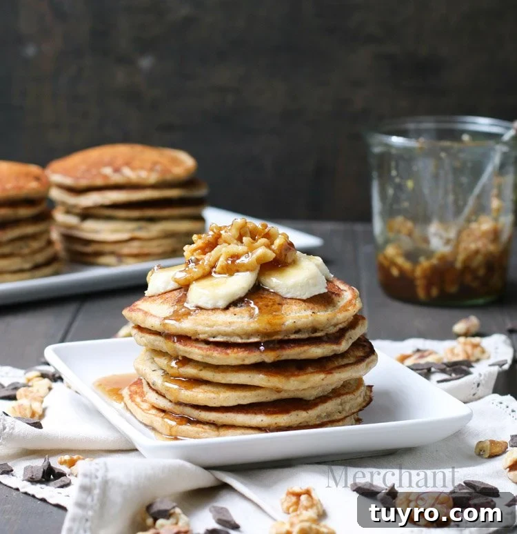 Stack of Oatmeal Chocolate Chip Banana Pancakes topped with sliced bananas and walnut syrup