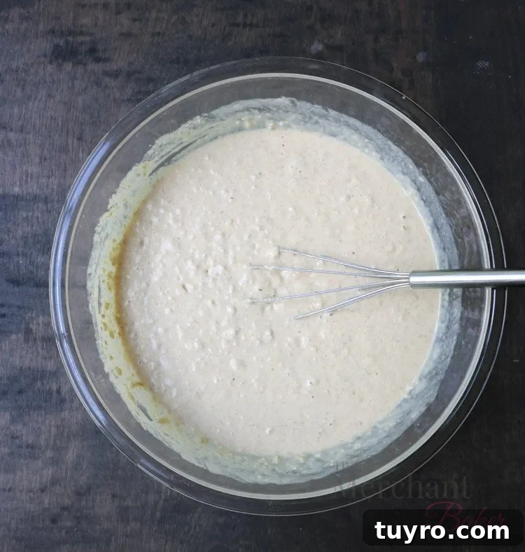 Bowl of Oatmeal Chocolate Chip Banana Pancake batter in a glass bowl with a whisk