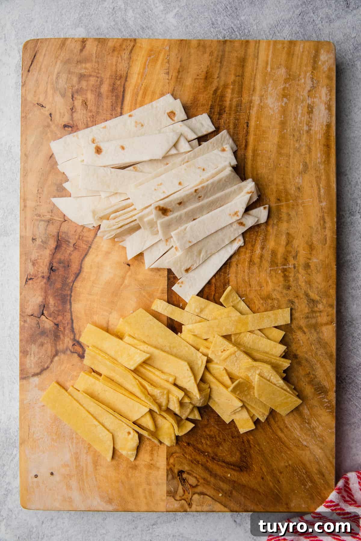 Crispy Air Fryer Tortilla Strips for Salads and Soups 4 Tortillas cut into strips on a cutting board.