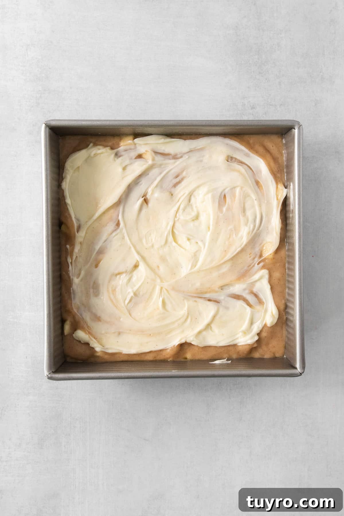 Homemade Apple Cream Cheese Coffee Cake Recipe 5 a pan filled with white frosting on top of a table.