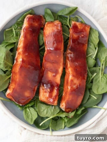 three pieces of bbq salmon on a bed of spinach