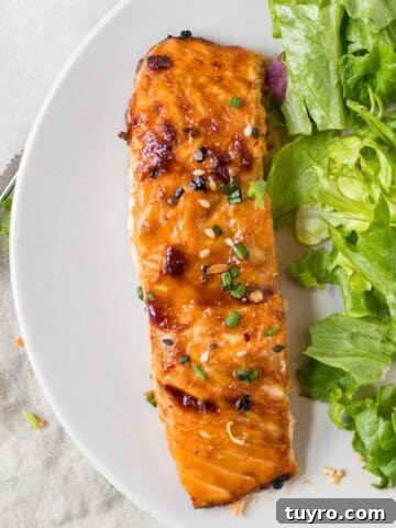 sesame ginger salmon on a white plate with a simple green salad.