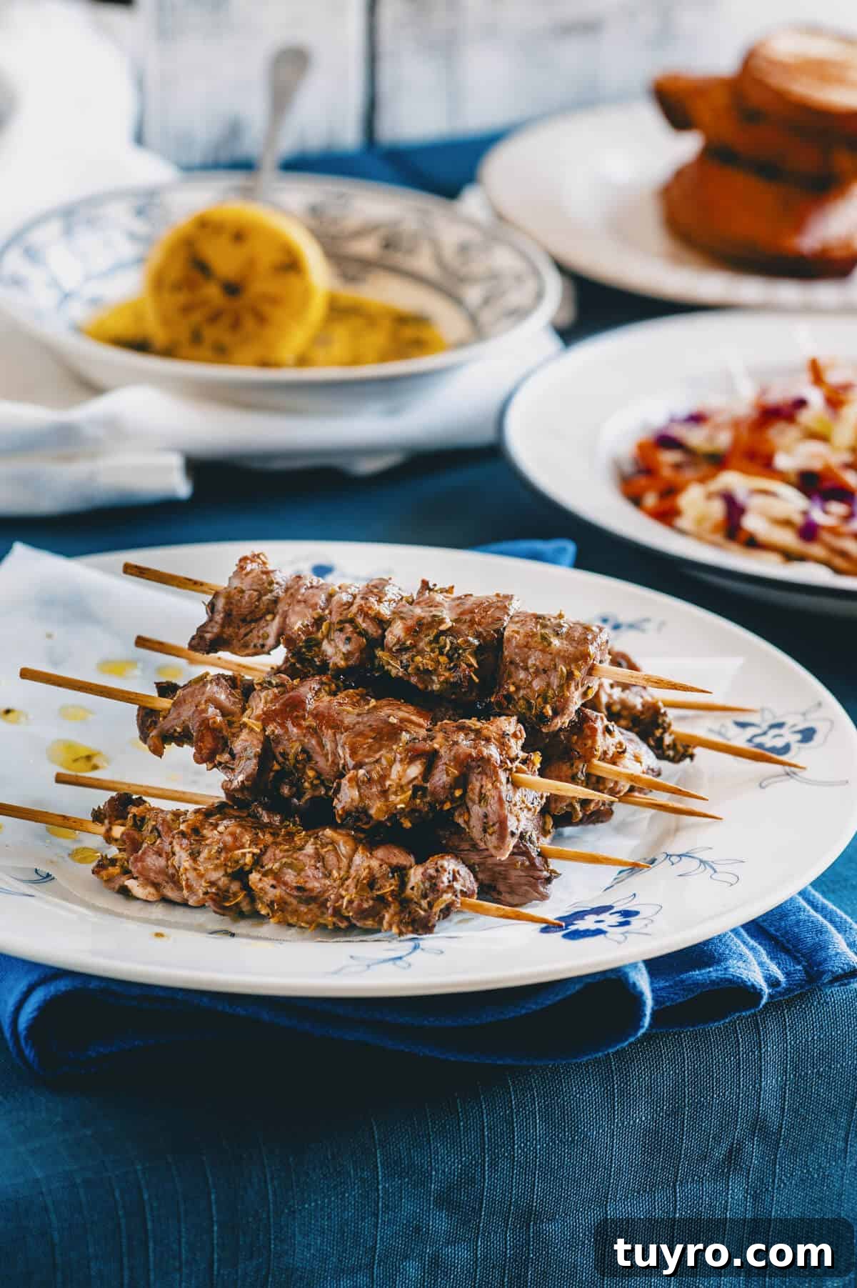 Souvlaki Explained: Your Guide to Greece’s Iconic Street Food 2 a plate of lamb souvlaki on a blue lined table.
