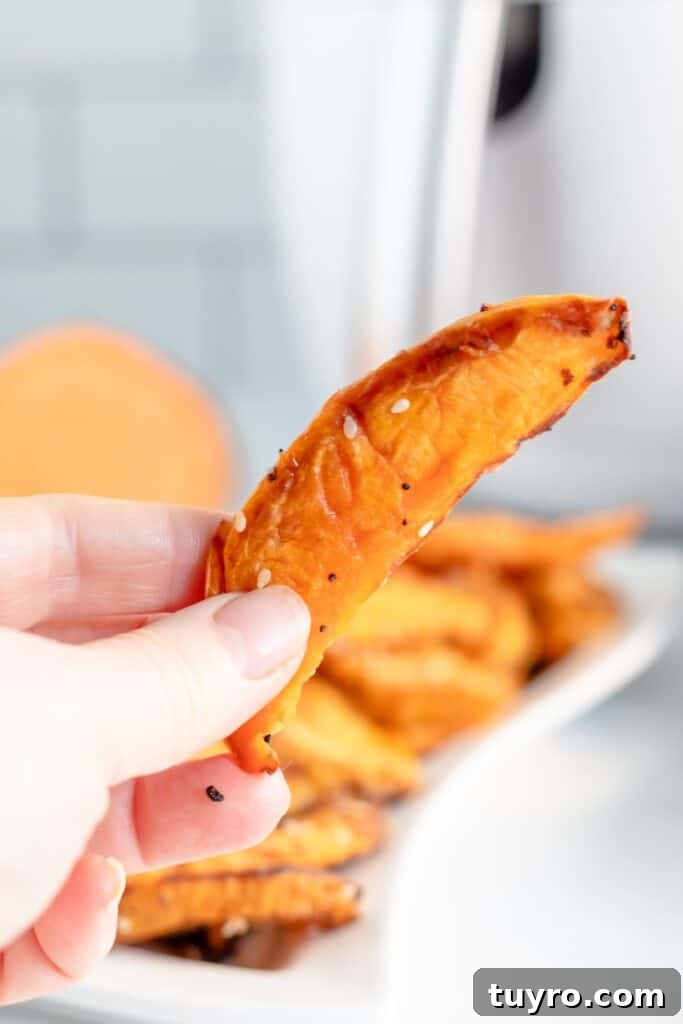 Crispy Air Fryer Sweet Potato Wedges Recipe 2 A hand holding a sweet potato wedge from the air fryer.