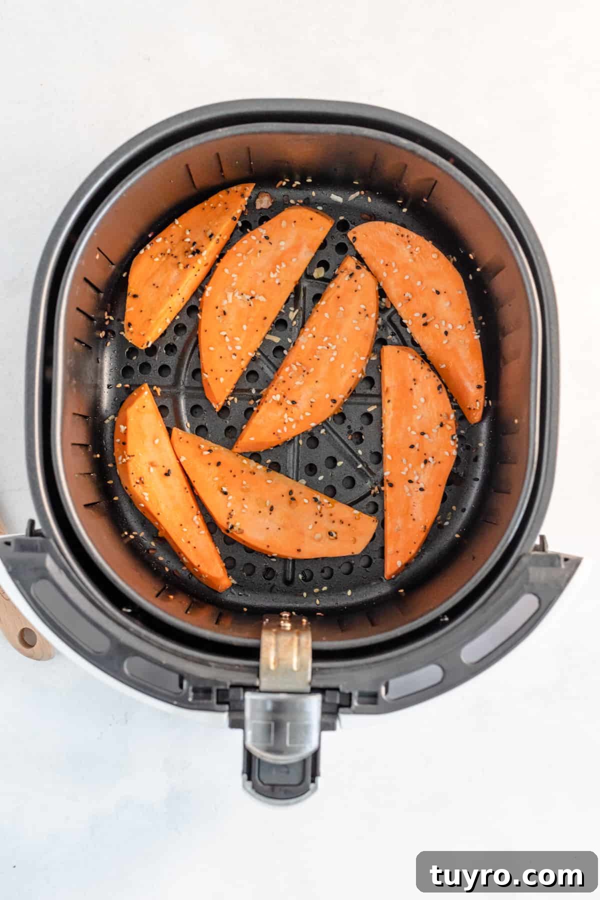 Crispy Air Fryer Sweet Potato Wedges Recipe 4 Seasoned sweet potato wedges in the air fryer basket, ready to cook.