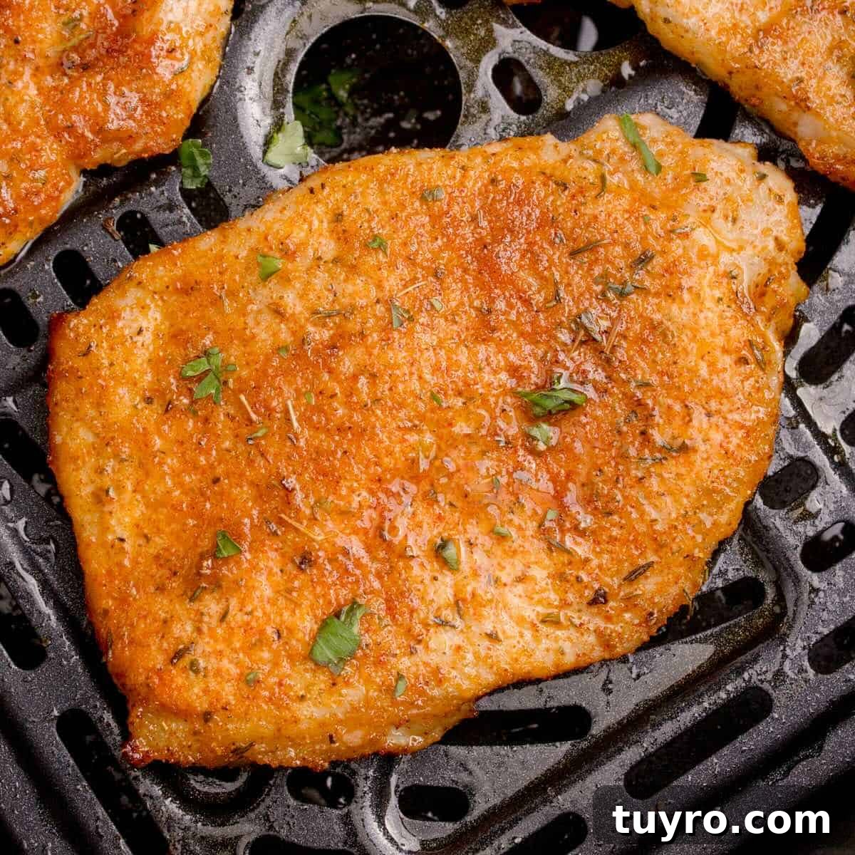 A cooked and seasoned thin pork chop in the air fryer basket.