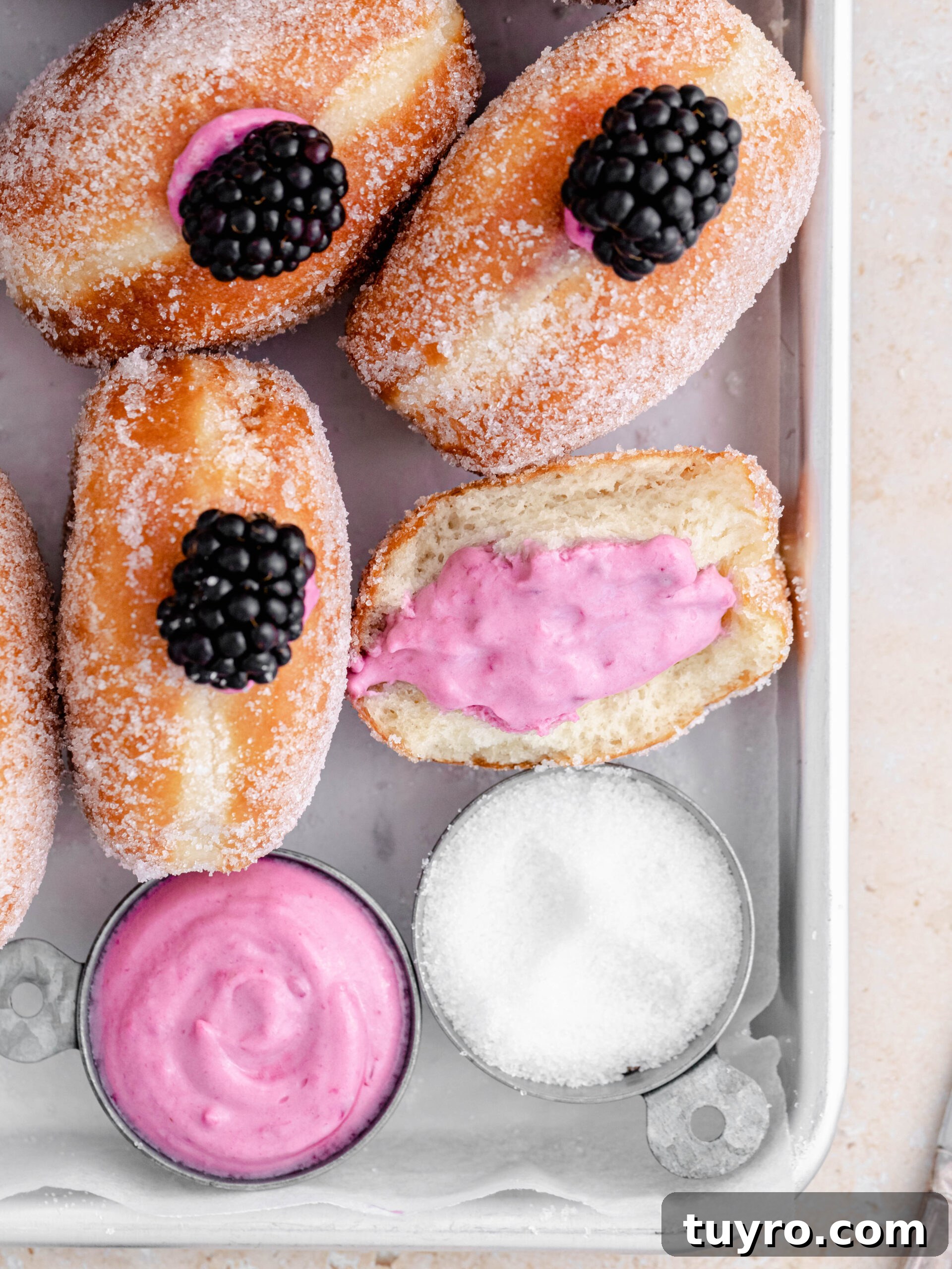 Blackberry Cheesecake Donuts with Creamy Filling 7 Delicious filled blackberry cheesecake donuts on a tray.