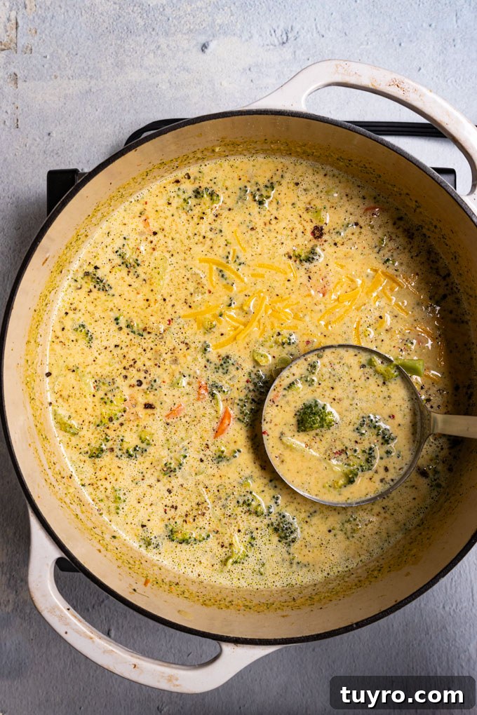 Creamy Broccoli Cheddar Soup Recipe with Gluten-Free Option 6 Overhead shot of soup in a white Dutch oven. A ladle is spooning up some of the soup. #foodphotography