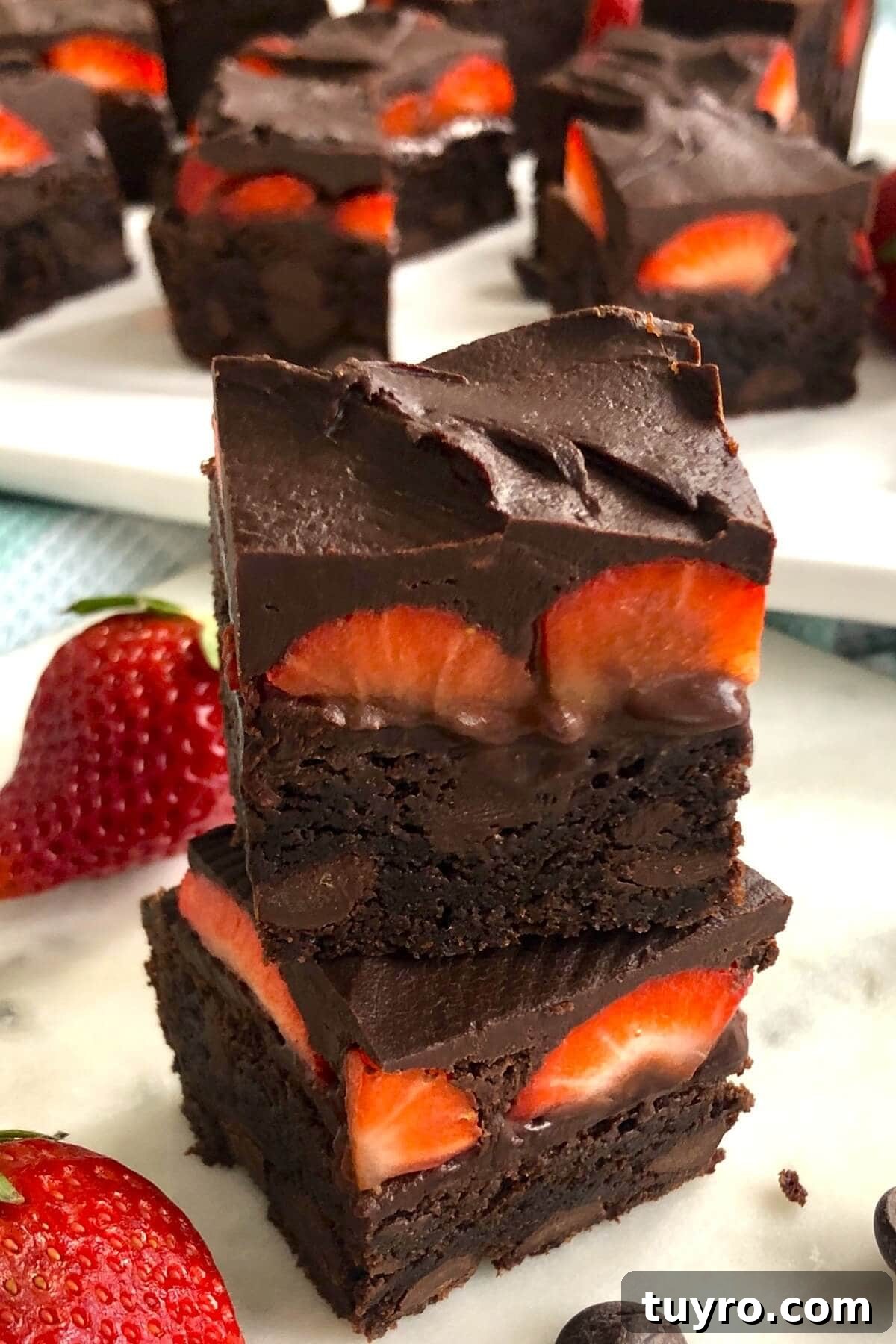 A stack of brownie with strawberries on a white marble board.