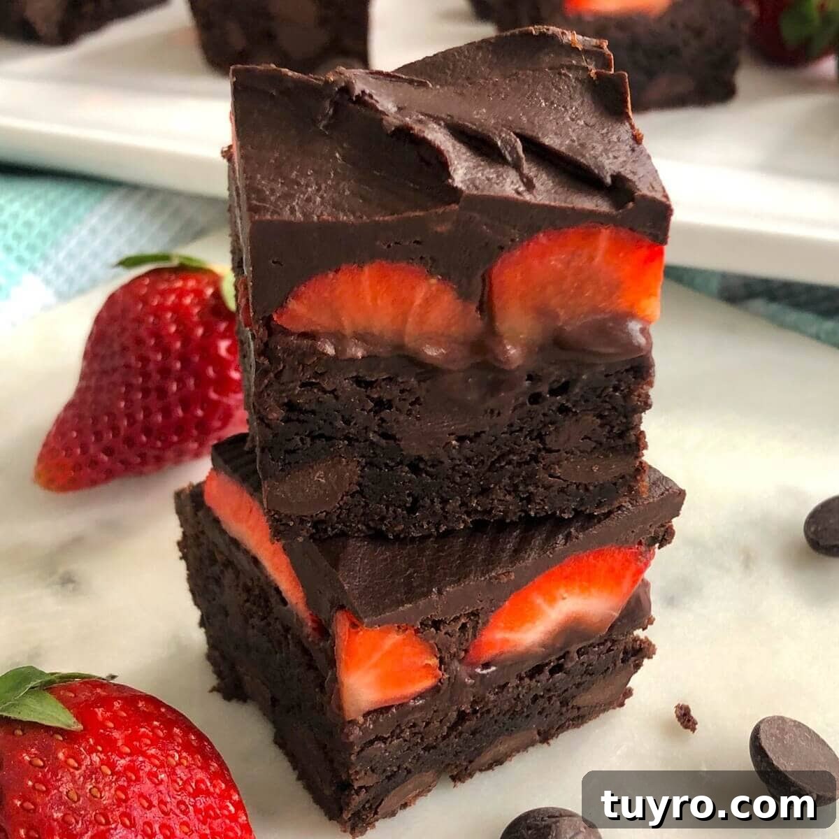 Two brownies with fresh strawberries topped with chocolate.