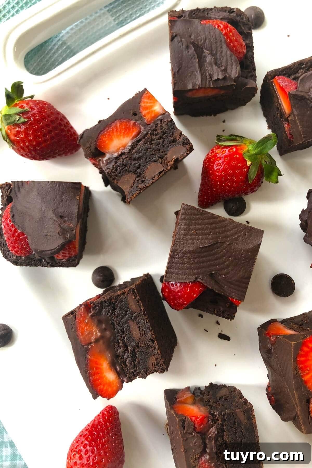 A white plate with cut brownies with strawberries.