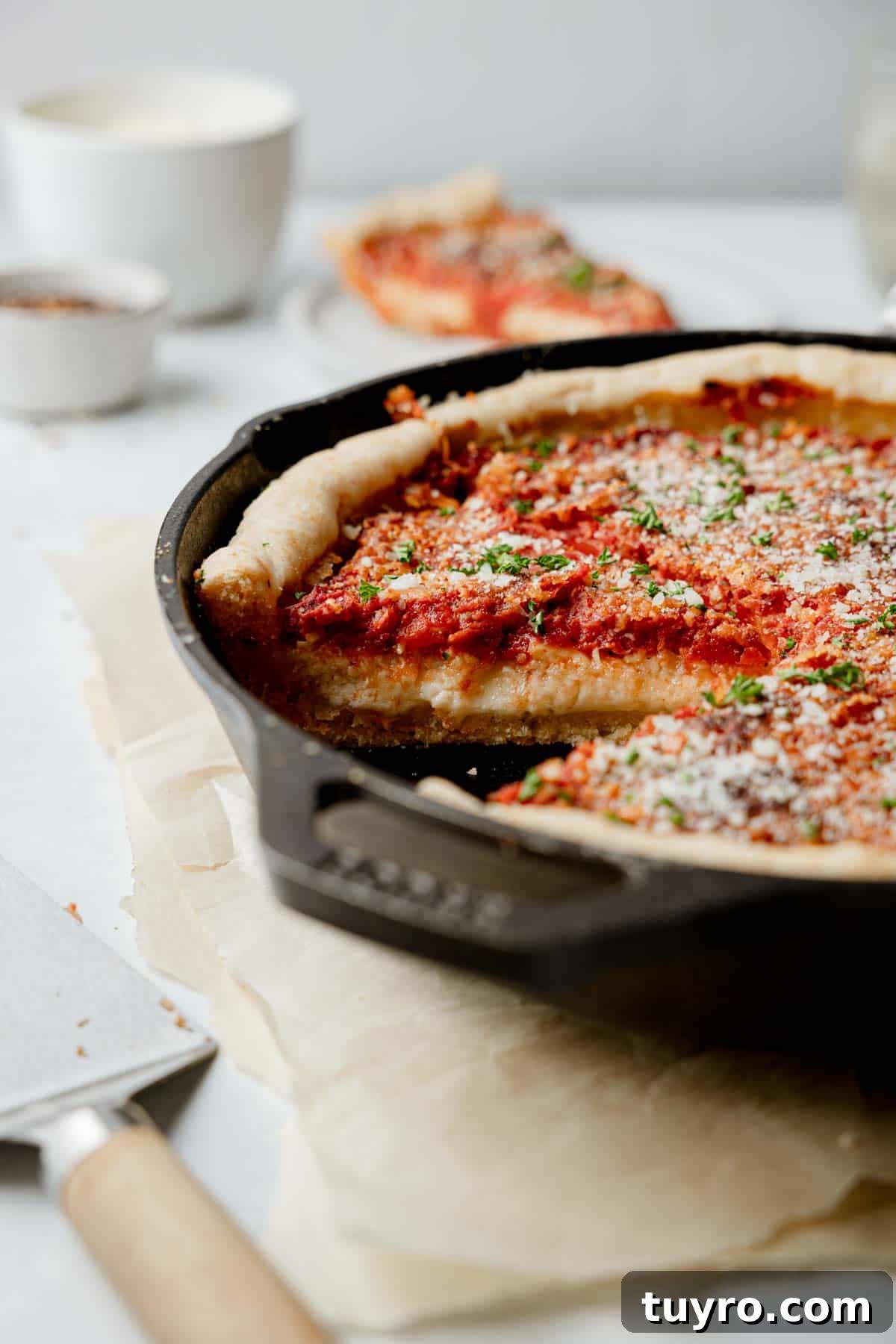 Authentic Chicago-Style Gluten-Free Deep Dish Pizza Recipe 2 Deep dish gluten free pizza in cast iron pan showing side of a slice with layers of cheese and sauce.