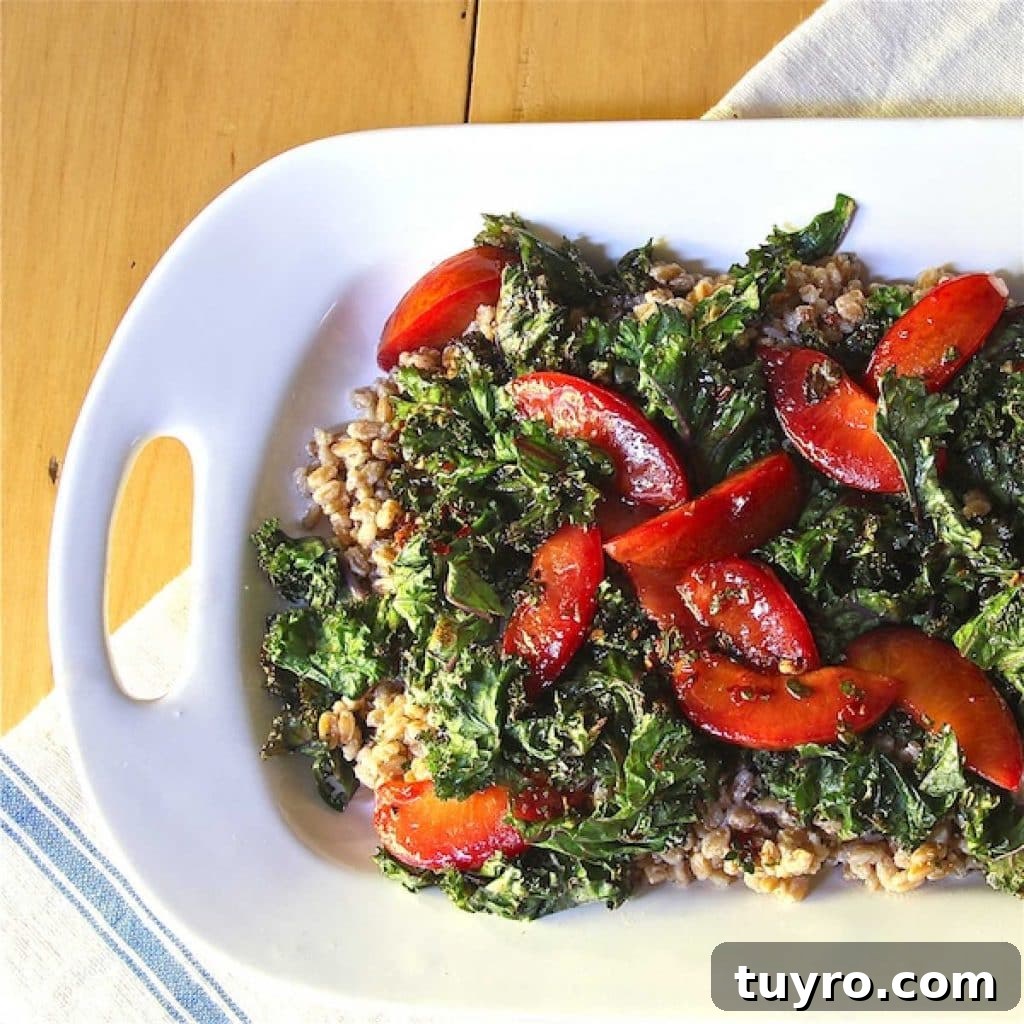 Serving platter of ricotta farro topped with a kale salad and plums.