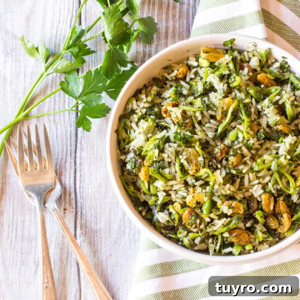 A bowl of cooked rice tossed with fresh herbs, scallions and raisins.