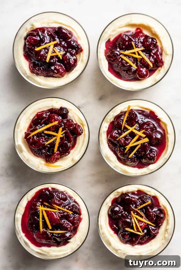 Mini No-Bake Cranberry Cheesecakes with Gingersnap Crust 9 Six no-bake cranberry cheesecakes in glass dishes lined up on a marble counter