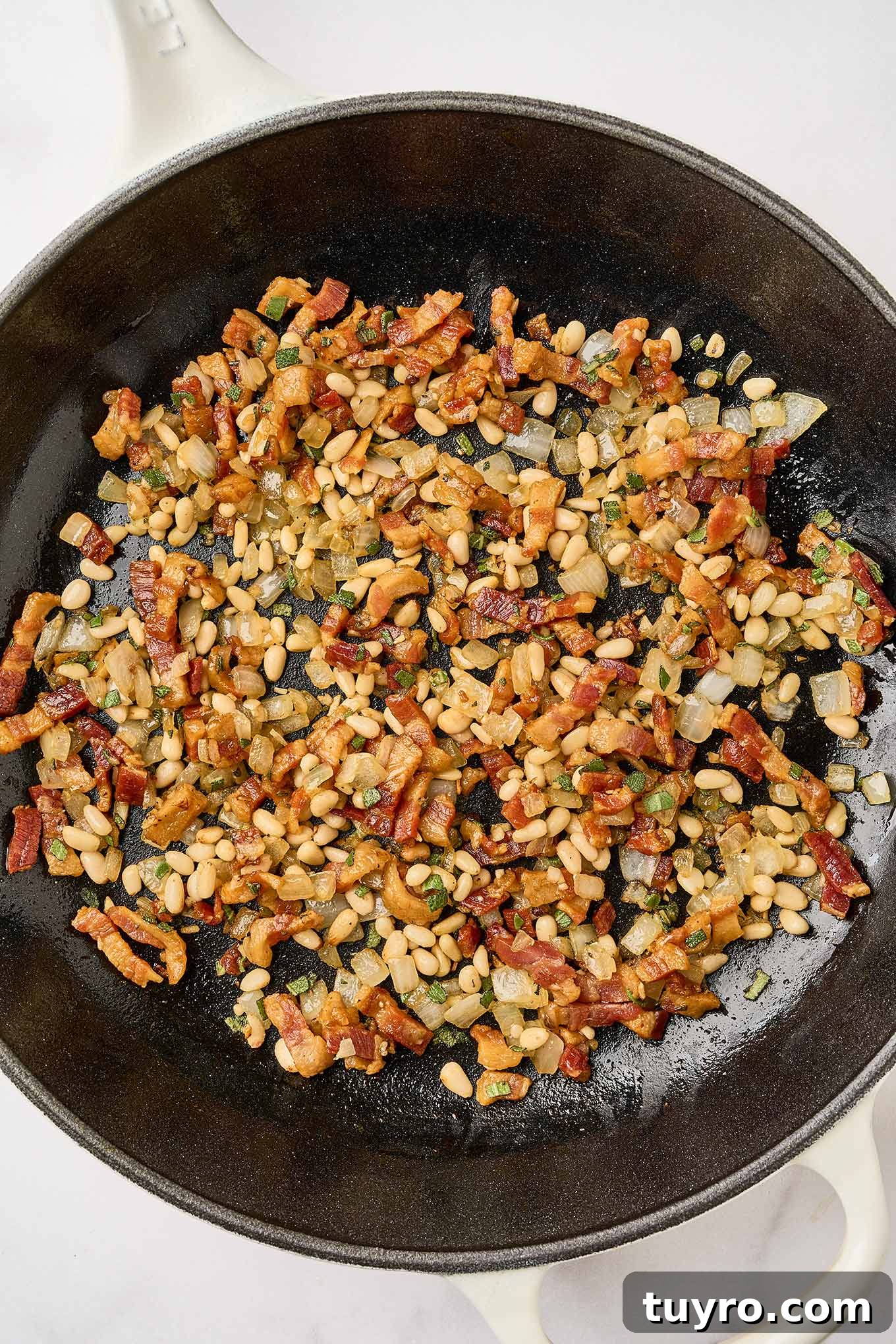 Creamy Pumpkin Pasta with Crispy Pancetta and Parmesan 5 Preparing creamy pumpkin pasta, by combining fried pancetta with sautéed onions, garlic, and pine nuts in a cast iron skillet.