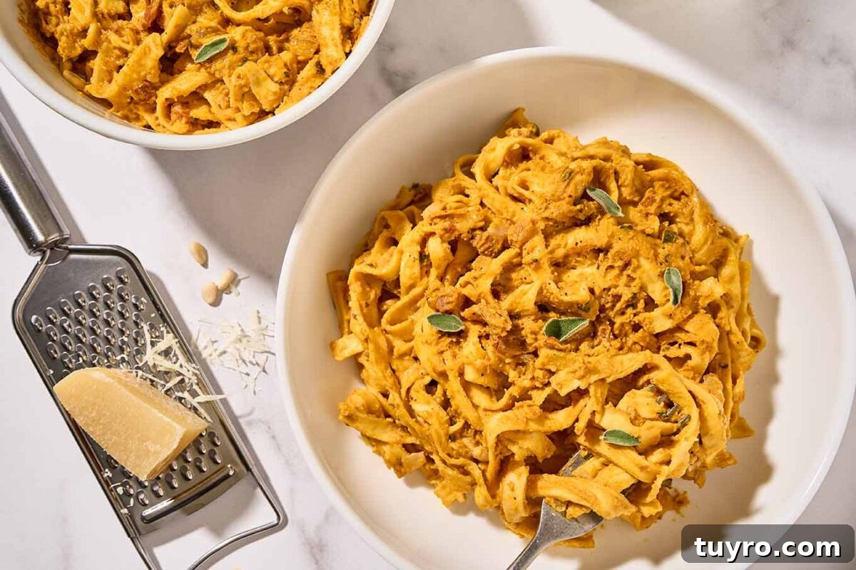 Creamy Pumpkin Pasta with Crispy Pancetta and Parmesan 8 Homemade creamy pumpkin pasta in white bowls with crispy pancetta, sage, and toasted pine nuts, a cheese grater and chunk of Parmesan to the side.