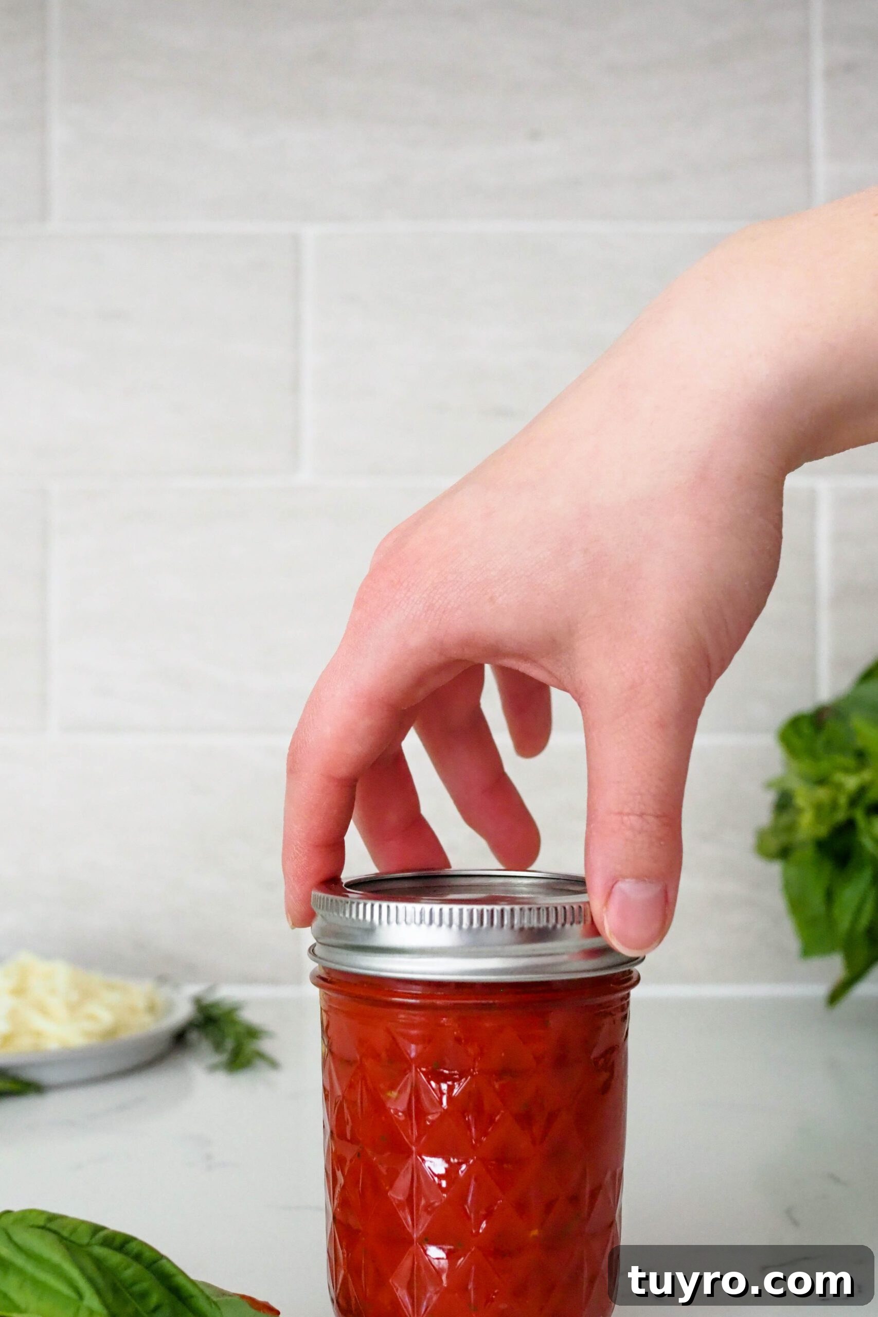 How to Make Pizza Sauce with Tomato Paste 6 A hand screws on the lid of a jar containing pizza sauce made from tomato paste.