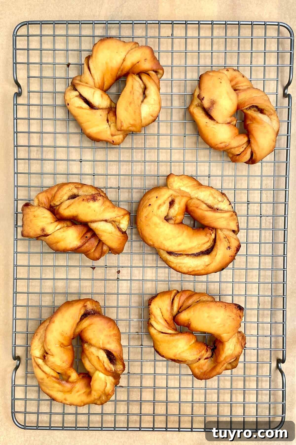Cinnamon Roll Donuts: Soft Swirls with Cream Cheese Glaze 16 Cooling donuts on rack.