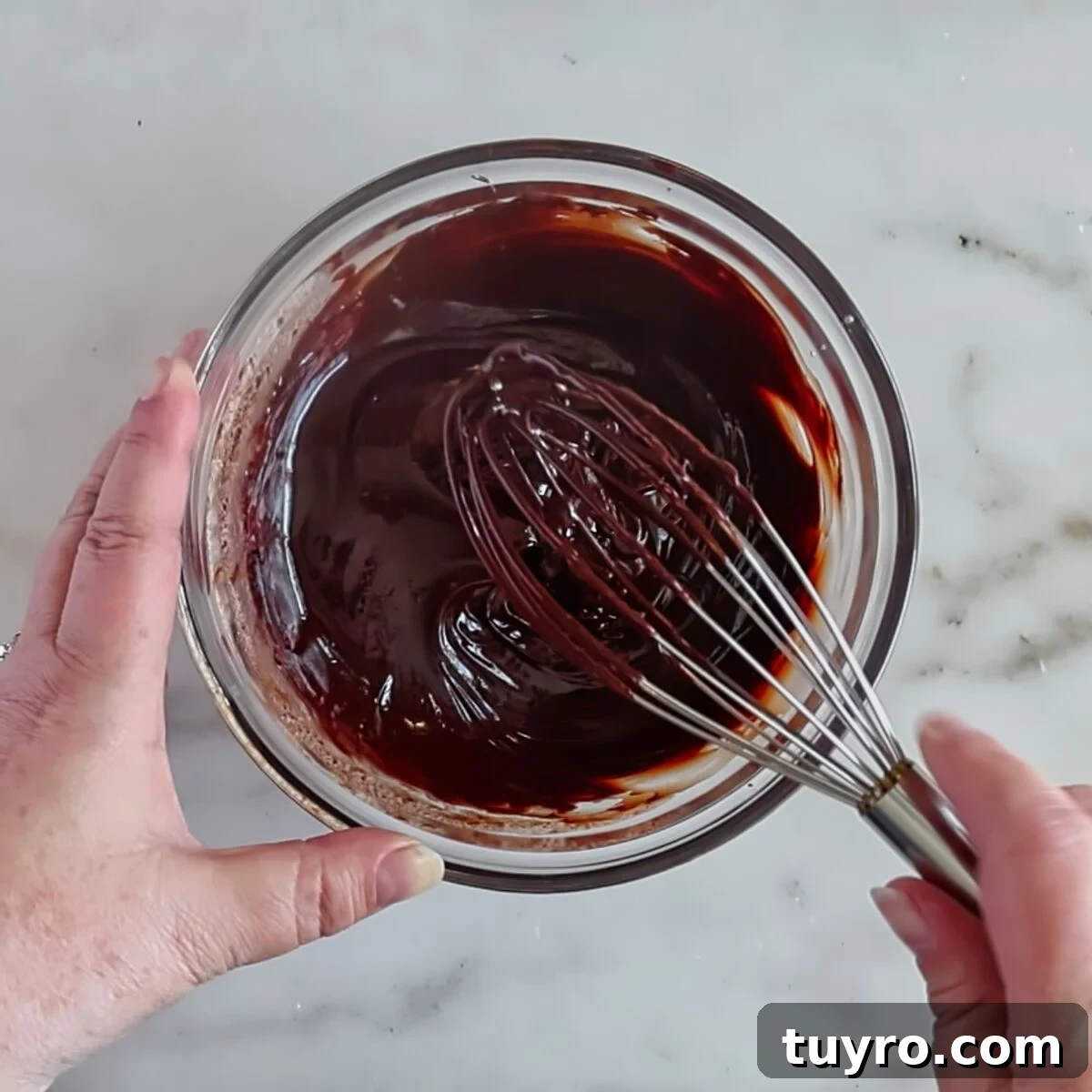 whisking chocolate ganache in glass bowl.