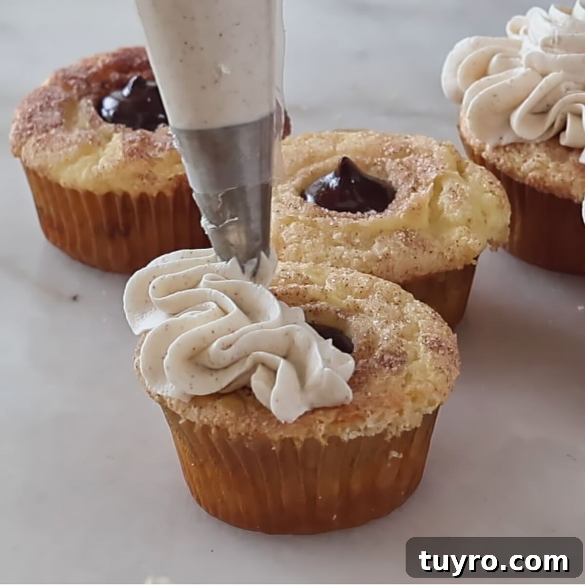 piping frosting on top of filled cupcakes.