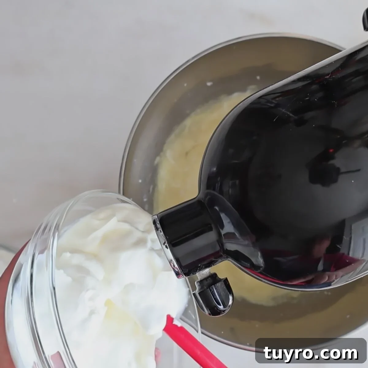 adding sour cream to batter in black stand mixer.