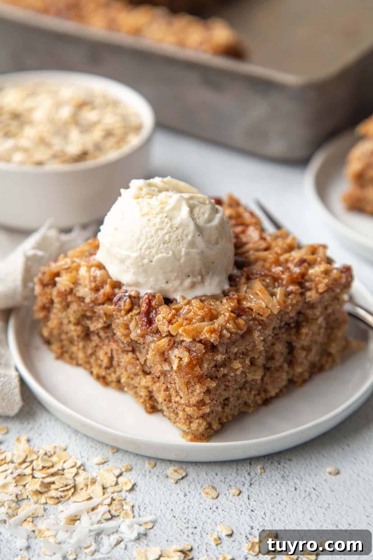 Classic Lazy Daisy Oatmeal Cake Recipe 2 oatmeal cake slice on a white plate, topped with a scoop of vanilla ice cream.