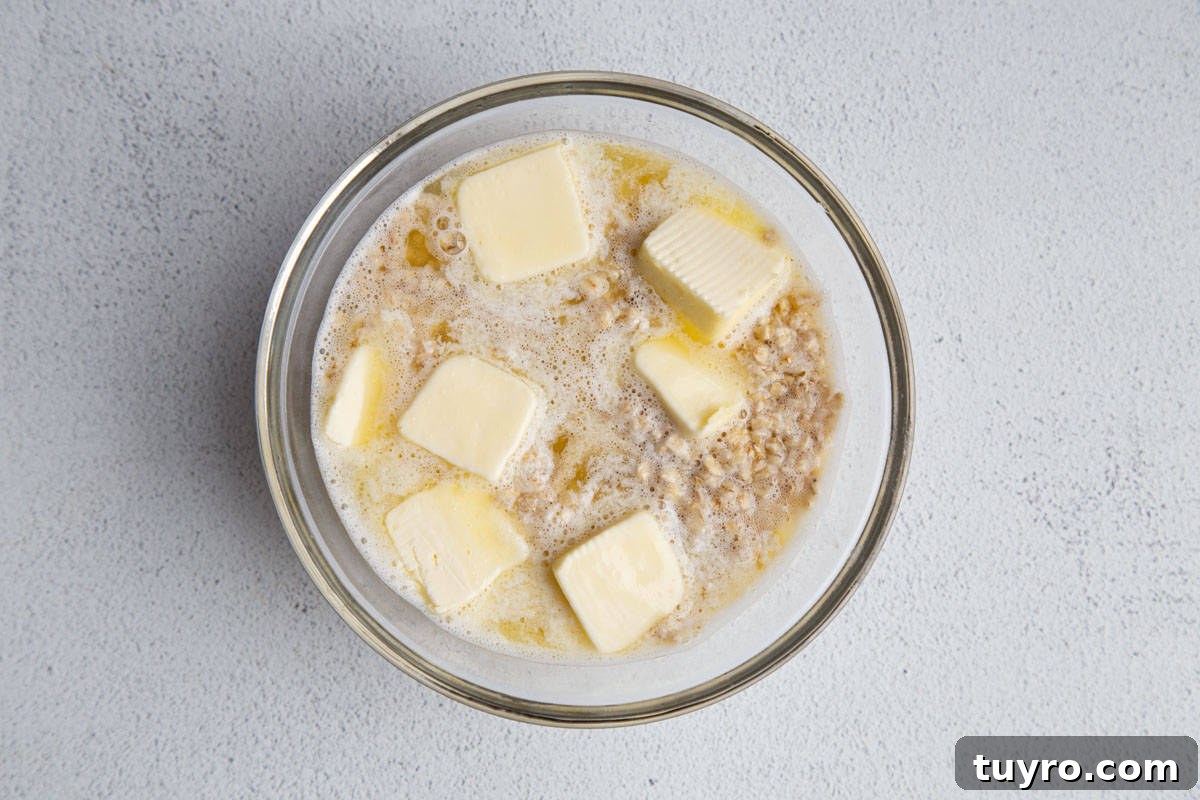 Classic Lazy Daisy Oatmeal Cake Recipe 4 oats and water in a glass bowl with pats of butter.