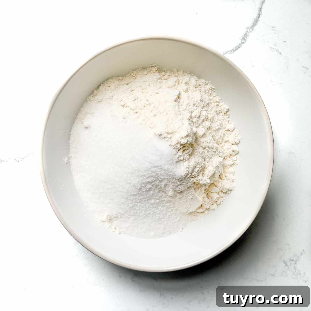Danish Pandekager: Crispy-Edged Pancakes Recipe 5 Adding the dry ingredients to a white bowl.