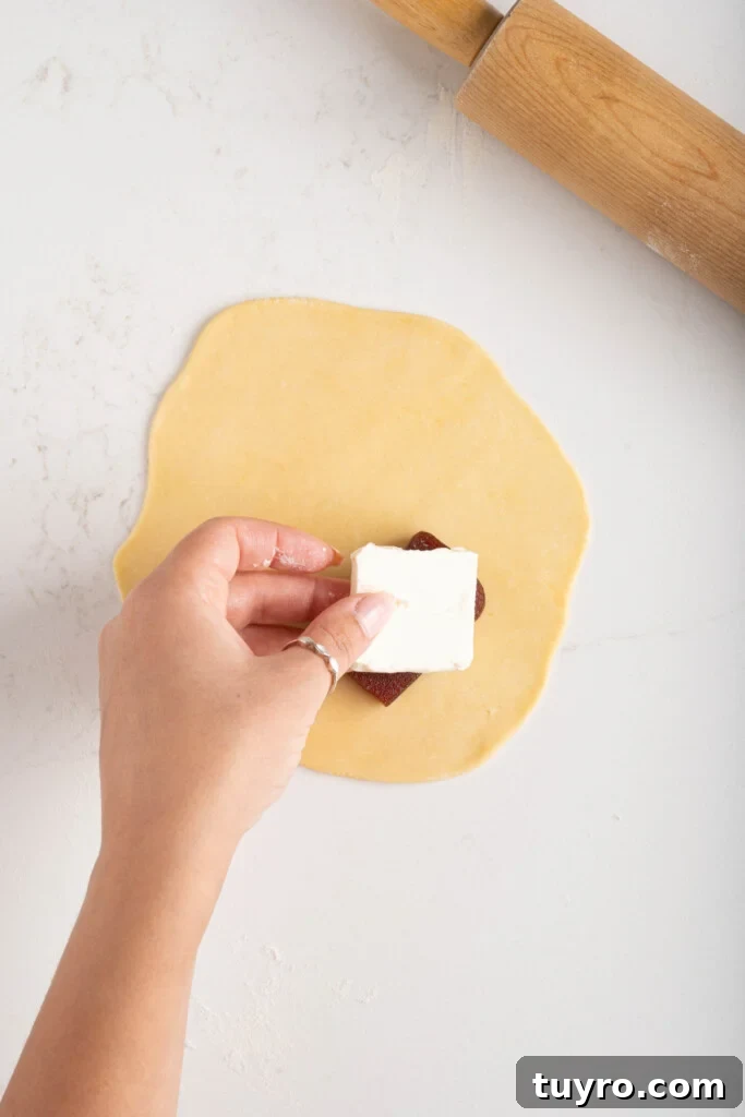 Guava Cheese Empanadas with 5 Ingredients — Quick Sweet Treat 8 a hand placing cheese over guava paste on empanada dough