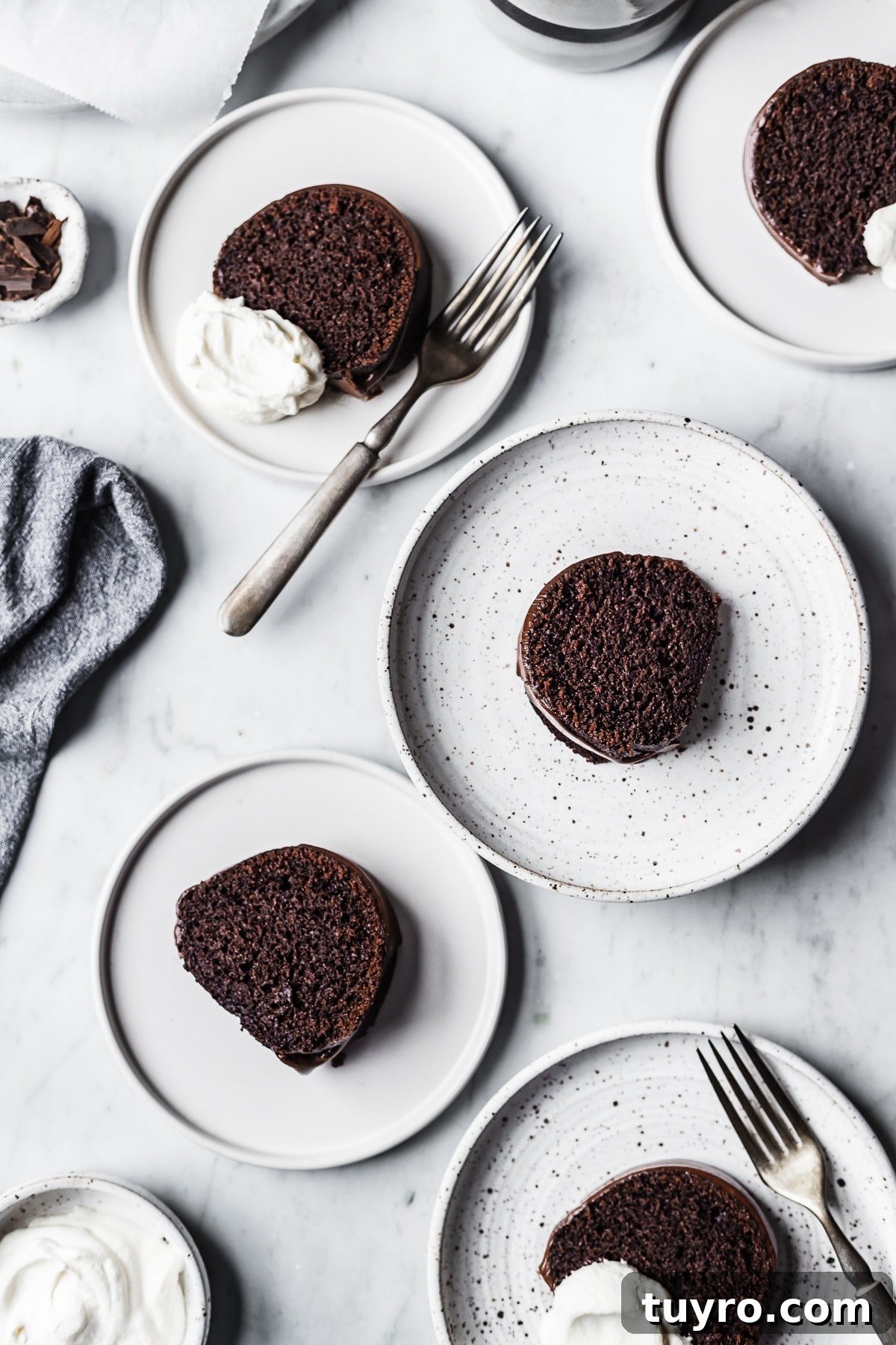 Five white plate each with a slice of chocolate bundt cake resting on a marble surface
