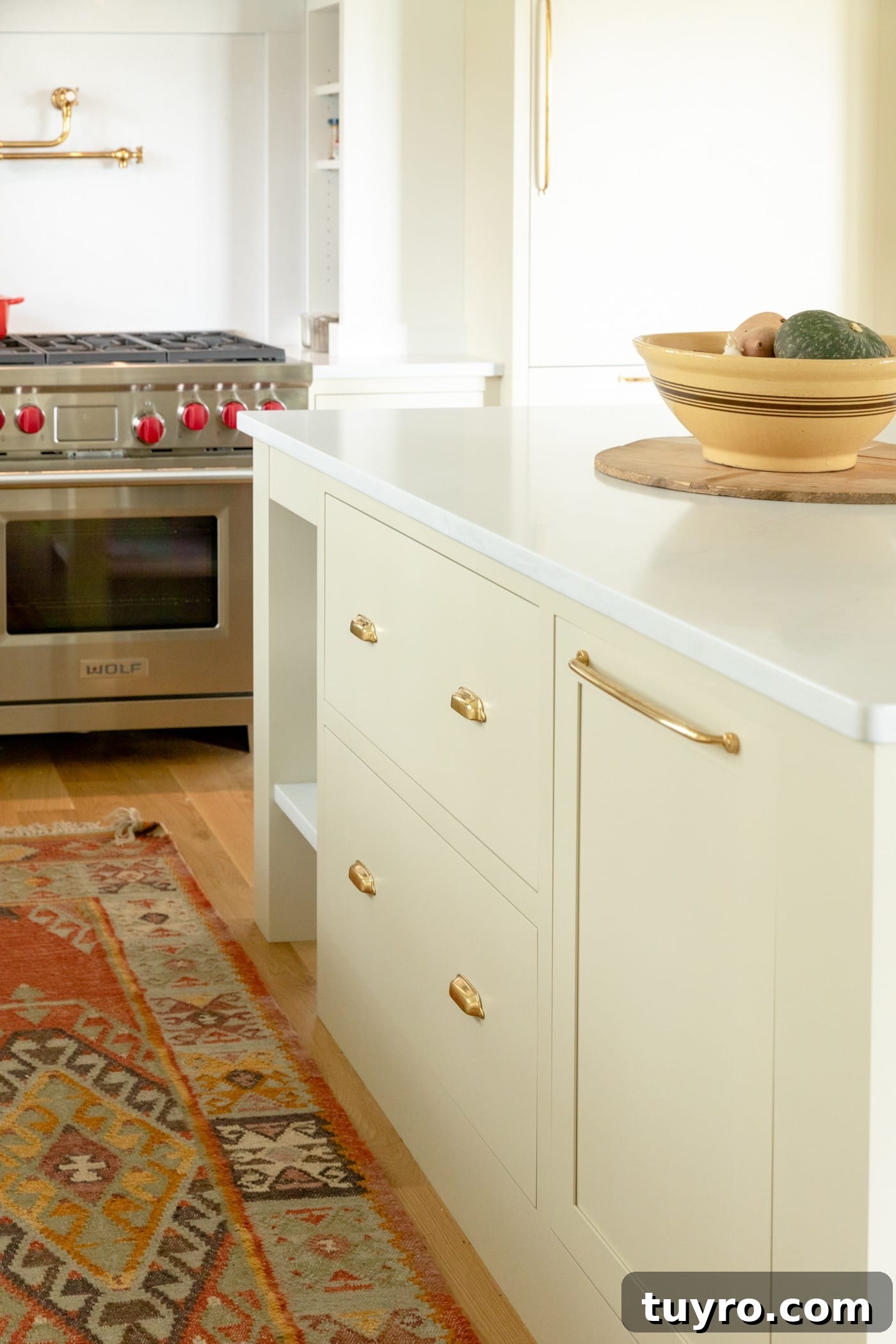 Large drawers in a kitchen island with range in background and red rug on hardwood floors
