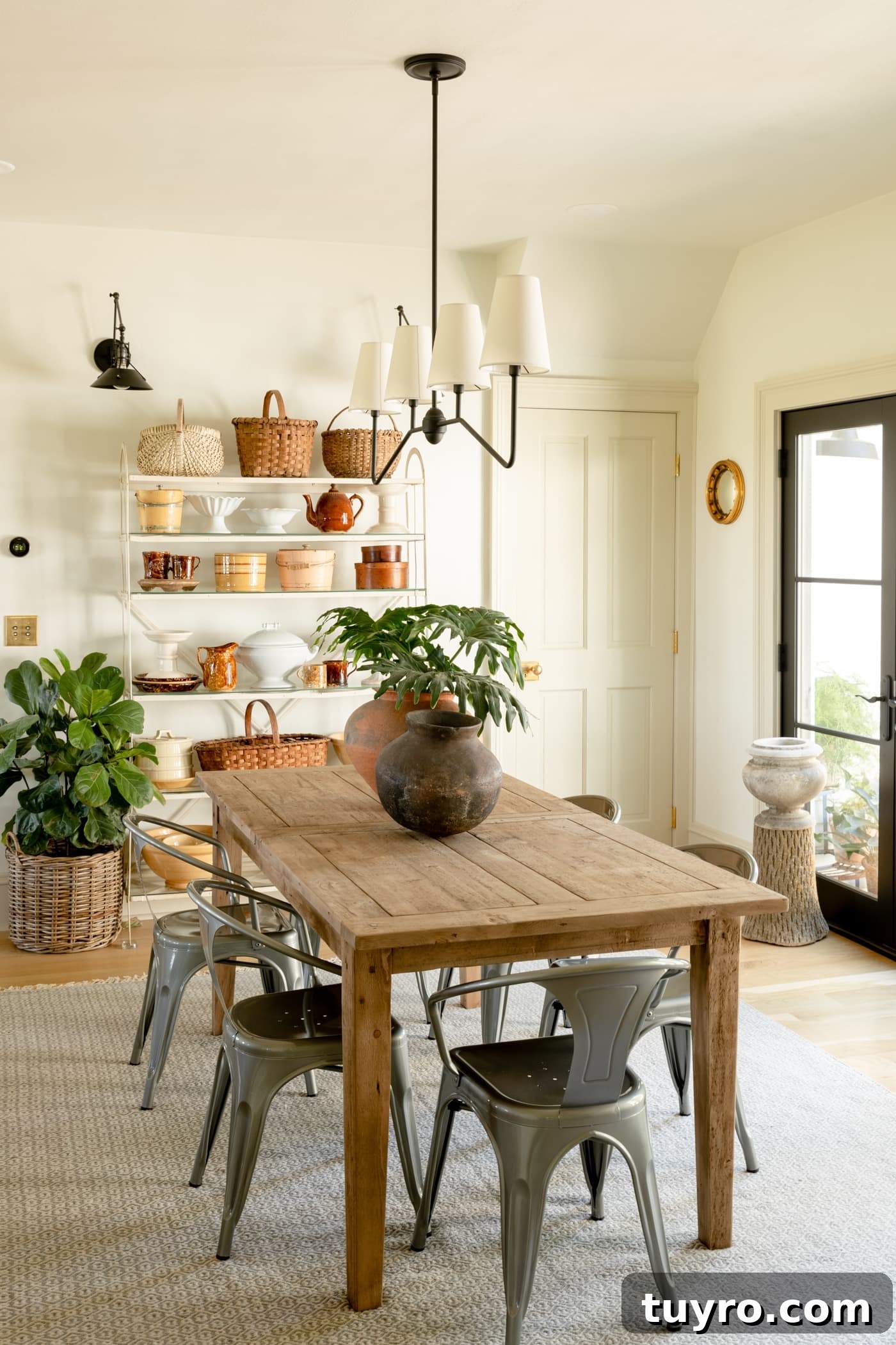 Light wood dining table with steel chairs and large white shelf stacked with brown and yellow decor with black French door to the side